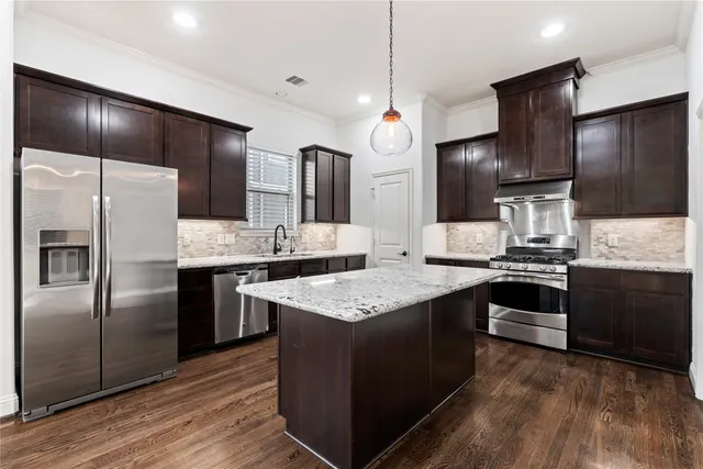 a kitchen with granite countertop stainless steel appliances a sink and refrigerator