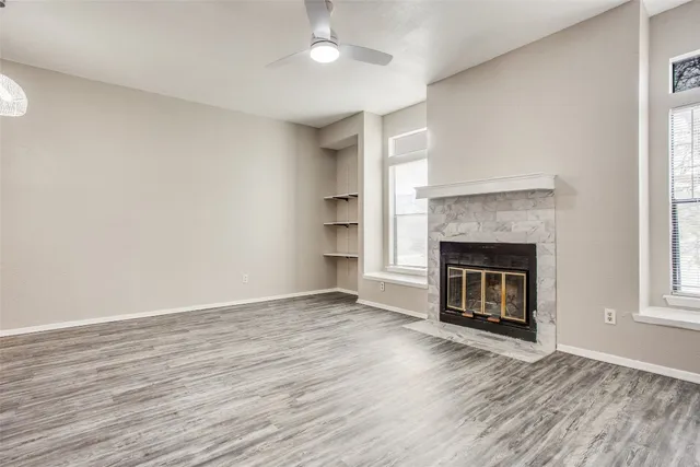 an empty room with wooden floor windows and a fireplace