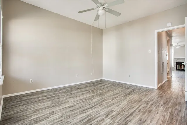 an empty room with wooden floor fan and windows