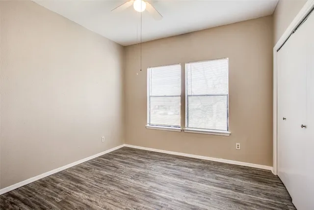 an empty room with wooden floor cabinet and windows