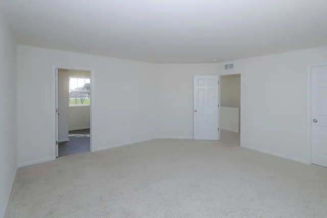 a view of an empty room with closet and a window