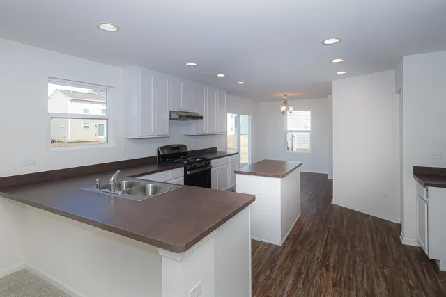 a kitchen with stainless steel appliances granite countertop a sink a stove a refrigerator and a microwave