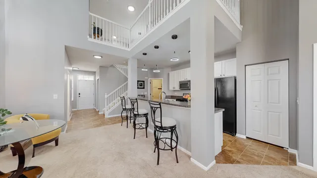 a dining hall with stainless steel appliances kitchen island granite countertop a refrigerator and cabinets