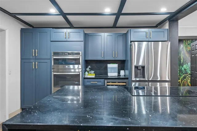 a view of a counter top space with stainless steel appliances granite countertop a sink and a refrigerator