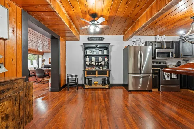 a living room with stainless steel appliances furniture wooden floor and a large window