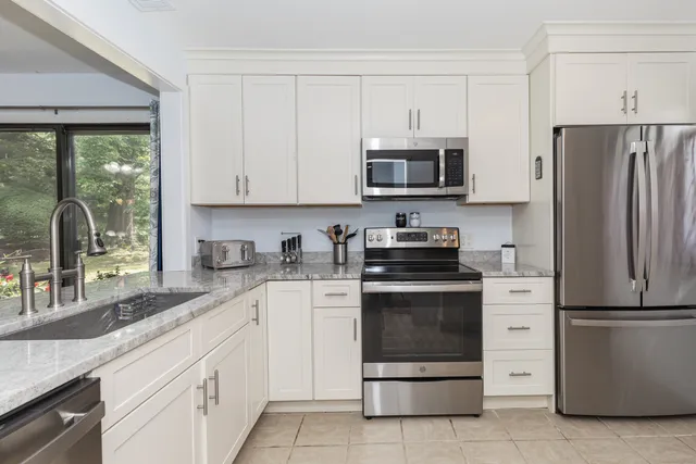 a kitchen with granite countertop white cabinets and stainless steel appliances