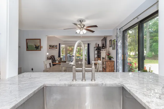 a view of a kitchen with granite countertop a sink a counter top space and living room view