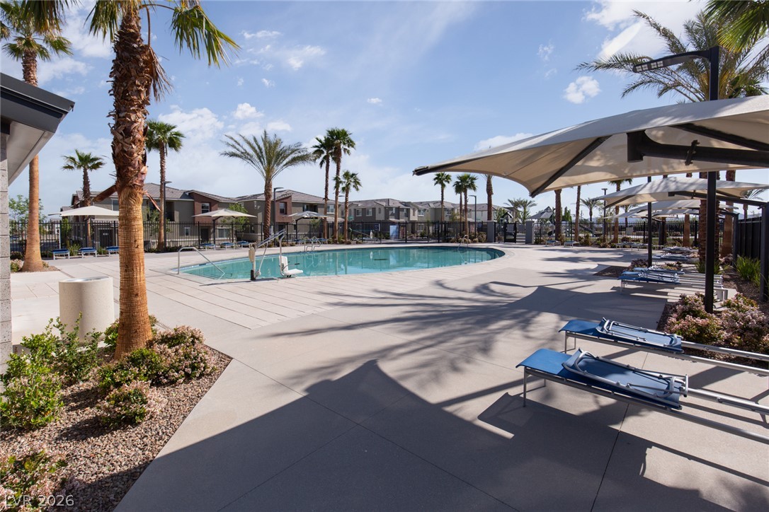 12232 Azure Gate Road, Unit 1 Las Vegas, NV 89183 - Photo 20 of 20 Palm trees surround a resort-style community swimming pool bordered by concrete decking under sunny skies.
