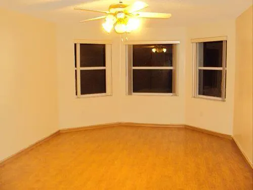a view of an empty room with a window and kitchen view