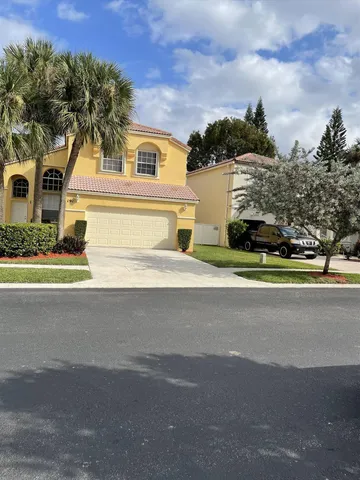 a front view of a house with a garden and tree