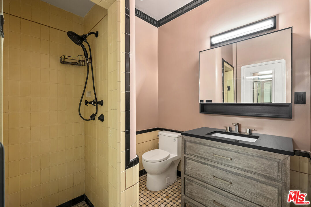 1326 Londonderry View Drive, Unit 4 Los Angeles, CA 90069 - Photo 27 of 29 a bathroom with a granite countertop sink toilet and a mirror