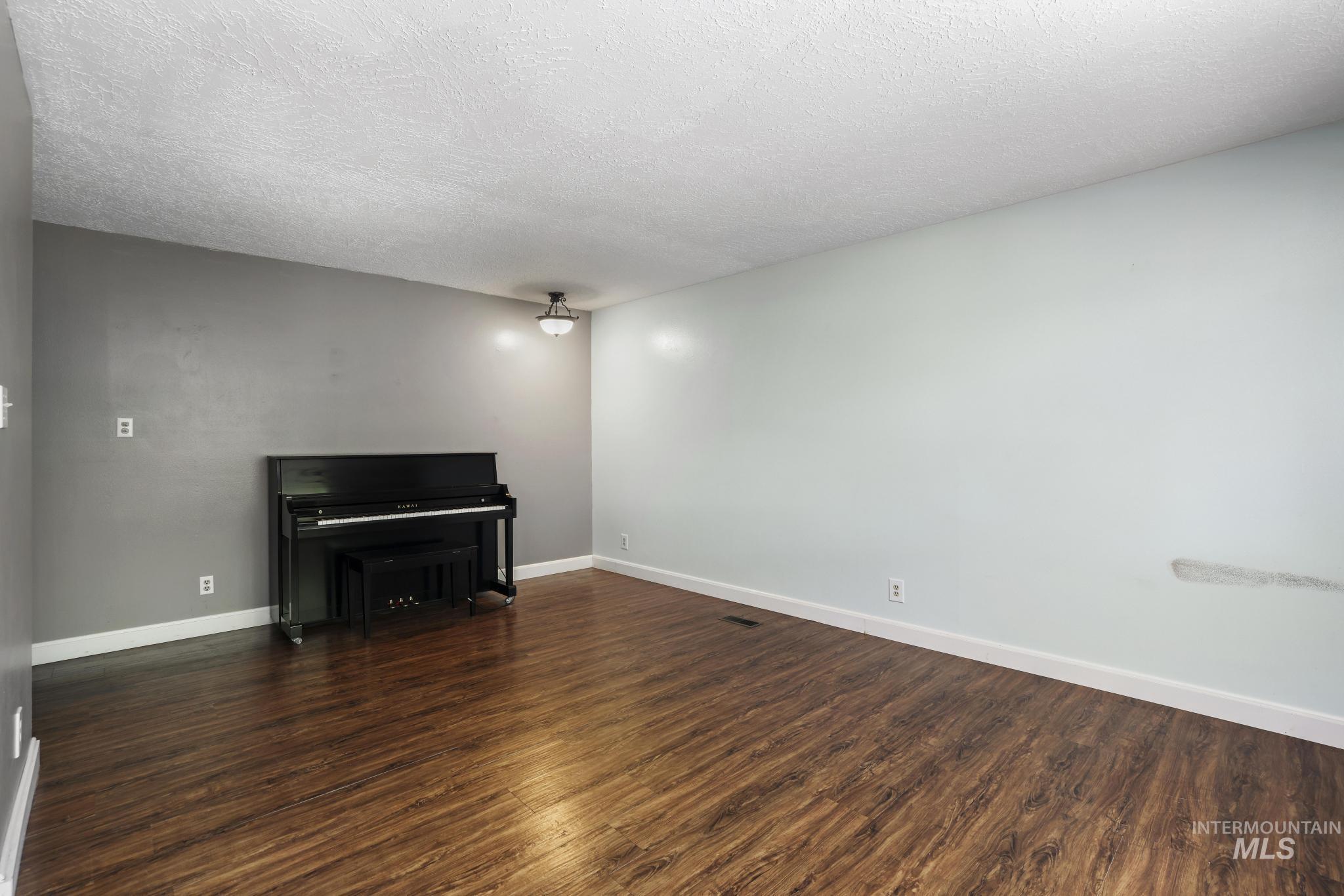 712 Locust Street Kimberly, ID 83341 - Photo 7 of 26 Spacious room featuring wood-finish flooring, white baseboards, and a large window