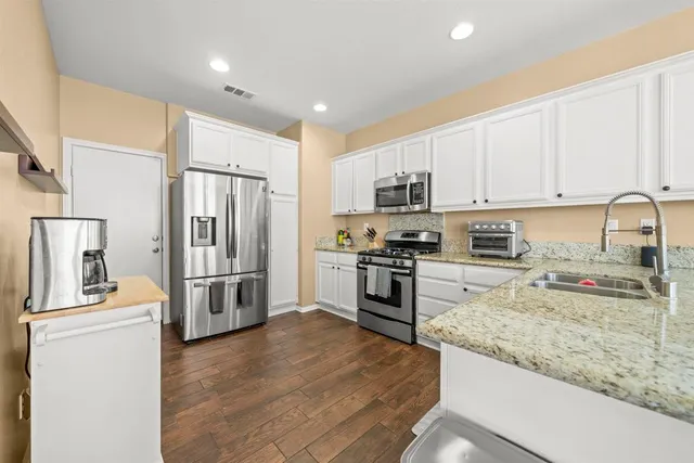 a kitchen with granite countertop a refrigerator stove and sink