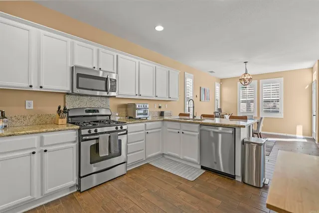 a kitchen with stainless steel appliances granite countertop a stove a sink and white cabinets