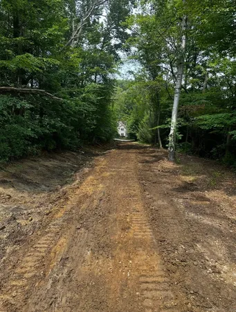a view of a white house next to a yard with potted plants