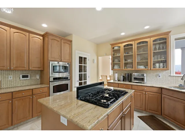 a kitchen with stainless steel appliances kitchen island granite countertop a sink counter space cabinets and a stove
