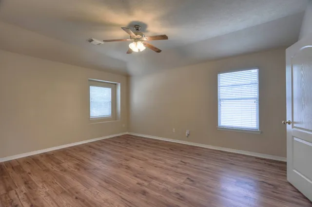 a view of empty room with window and wooden floor