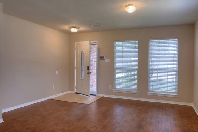 an empty room with wooden floor and windows