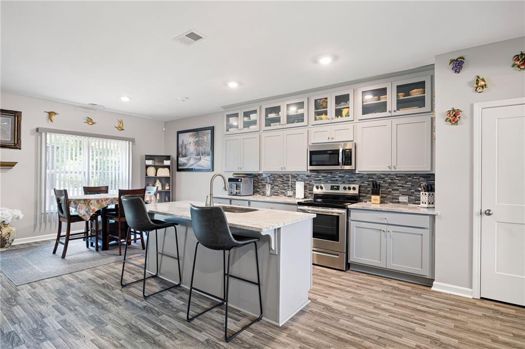 406 Splash Pointe Temple, GA 30179 - Photo 11 of 33 a kitchen with stainless steel appliances granite countertop a stove top oven a sink dishwasher a dining table and chairs with wooden floor
