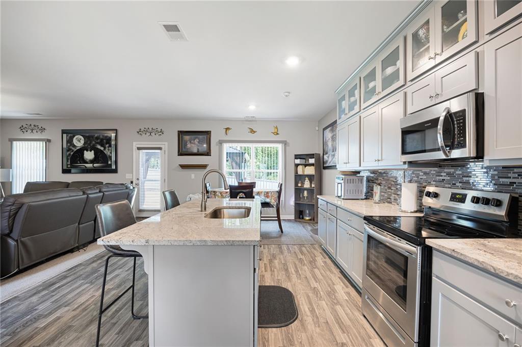 406 Splash Pointe Temple, GA 30179 - Photo 13 of 33 a large kitchen with stainless steel appliances granite countertop a stove top oven a sink dishwasher a dining table and chairs with wooden floor