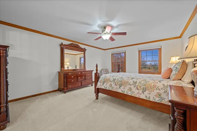 a spacious bedroom with a bed a dresser and a chandelier