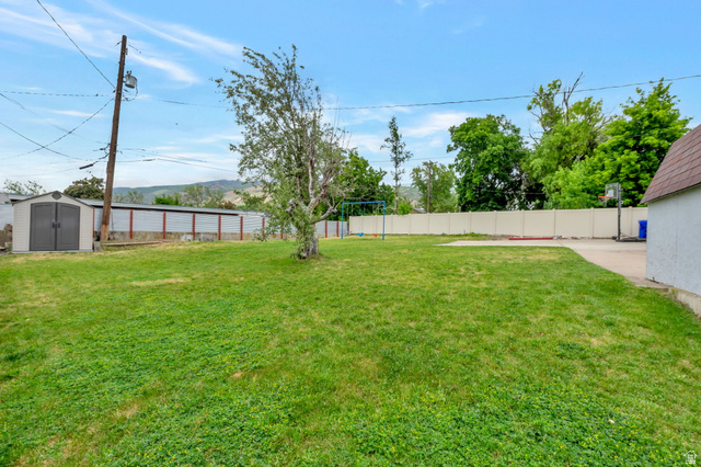 447 550 South Bountiful, UT 84010 - Photo 23 of 25 Expansive grassy backyard featuring a paved area, a storage shed, and perimeter fencing