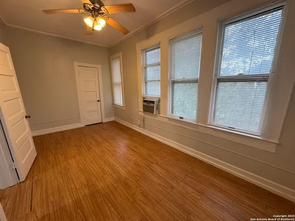 a view of an empty room with a window and wooden floor