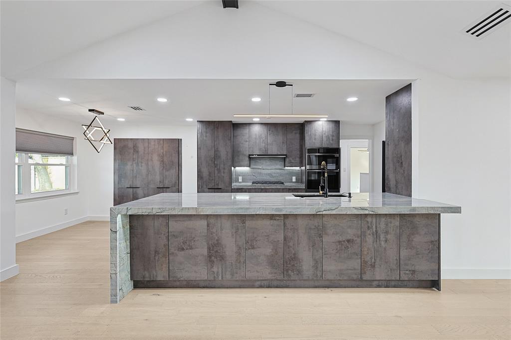 12417 Quincy Lane Dallas, TX 75230 - Photo 15 of 40 a large kitchen with stainless steel appliances kitchen island a large counter top and a fireplace