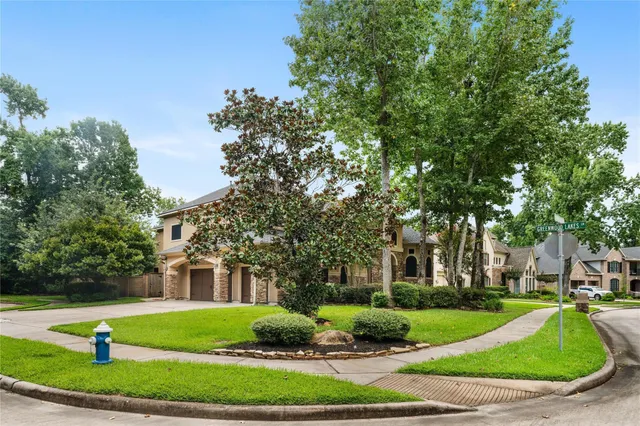 a view of a white house next to a yard with big trees