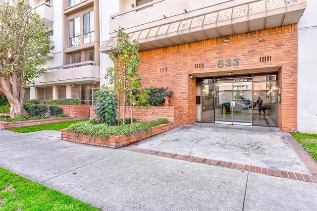 a front view of a building with a garden and plants