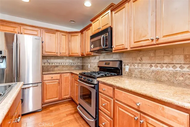 a kitchen with stainless steel appliances granite countertop a stove a sink and a refrigerator