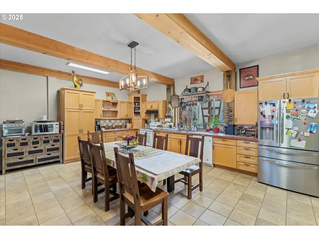 a kitchen with stainless steel appliances kitchen island granite countertop a table chairs sink and cabinets