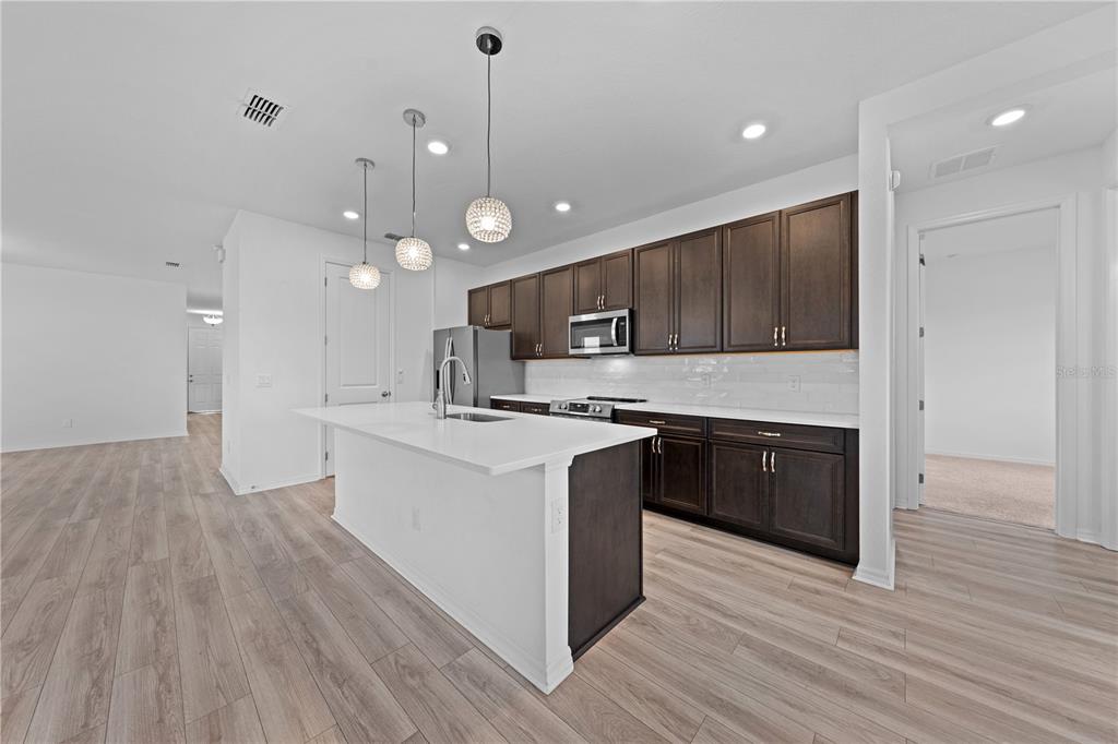 920 Livestock Loop St. Cloud, FL 34771 - Photo 11 of 55 a large kitchen with stainless steel appliances granite countertop a stove a sink and a refrigerator