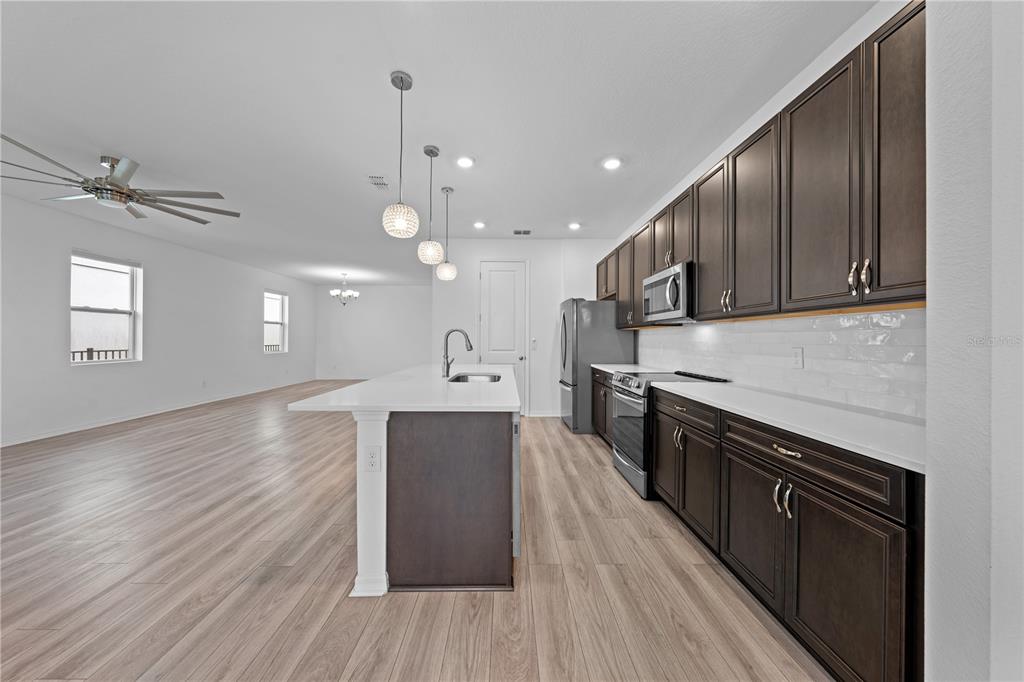 920 Livestock Loop St. Cloud, FL 34771 - Photo 14 of 55 a kitchen with stainless steel appliances granite countertop wooden cabinets a stove top oven a sink and dishwasher with wooden floor