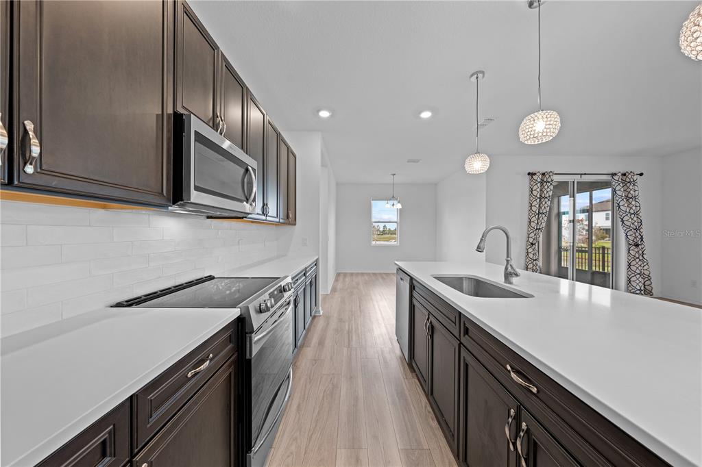 920 Livestock Loop St. Cloud, FL 34771 - Photo 7 of 55 a kitchen with cabinets wooden floor and stainless steel appliances