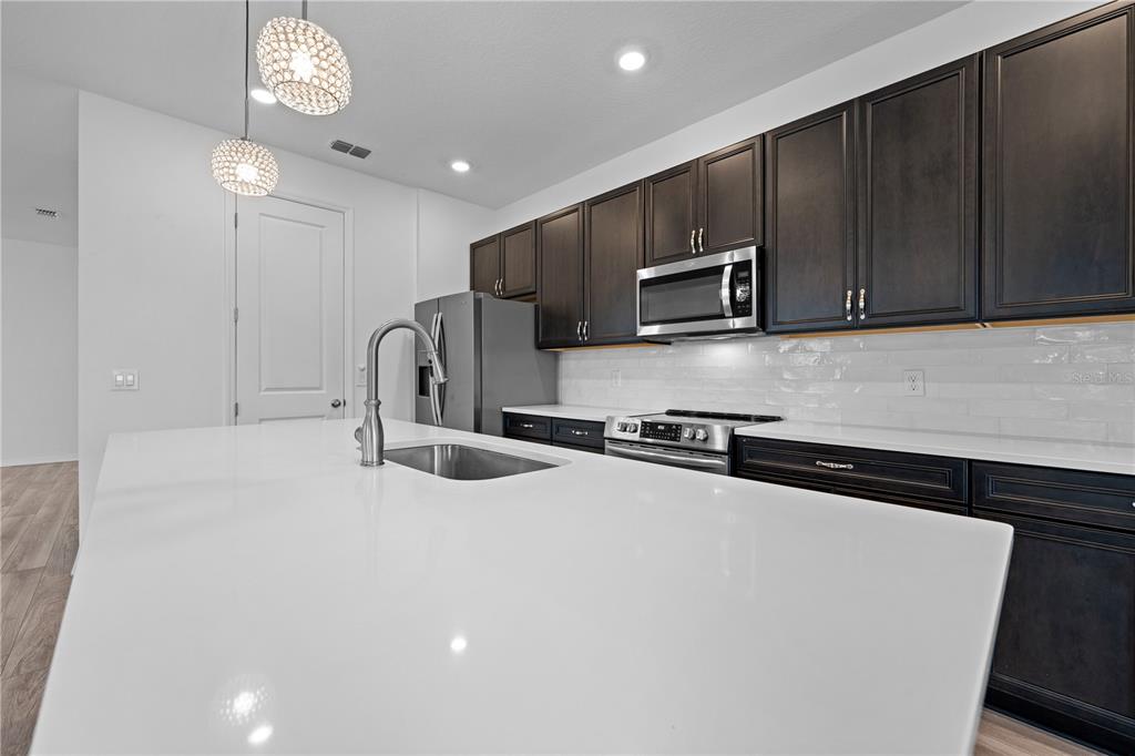 920 Livestock Loop St. Cloud, FL 34771 - Photo 8 of 55 a kitchen with stainless steel appliances a sink a stove a microwave a sink a refrigerator and cabinets
