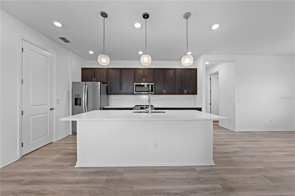 920 Livestock Loop St. Cloud, FL 34771 - Photo 10 of 55 a large white kitchen with a large island oven a refrigerator a sink and kitchen island