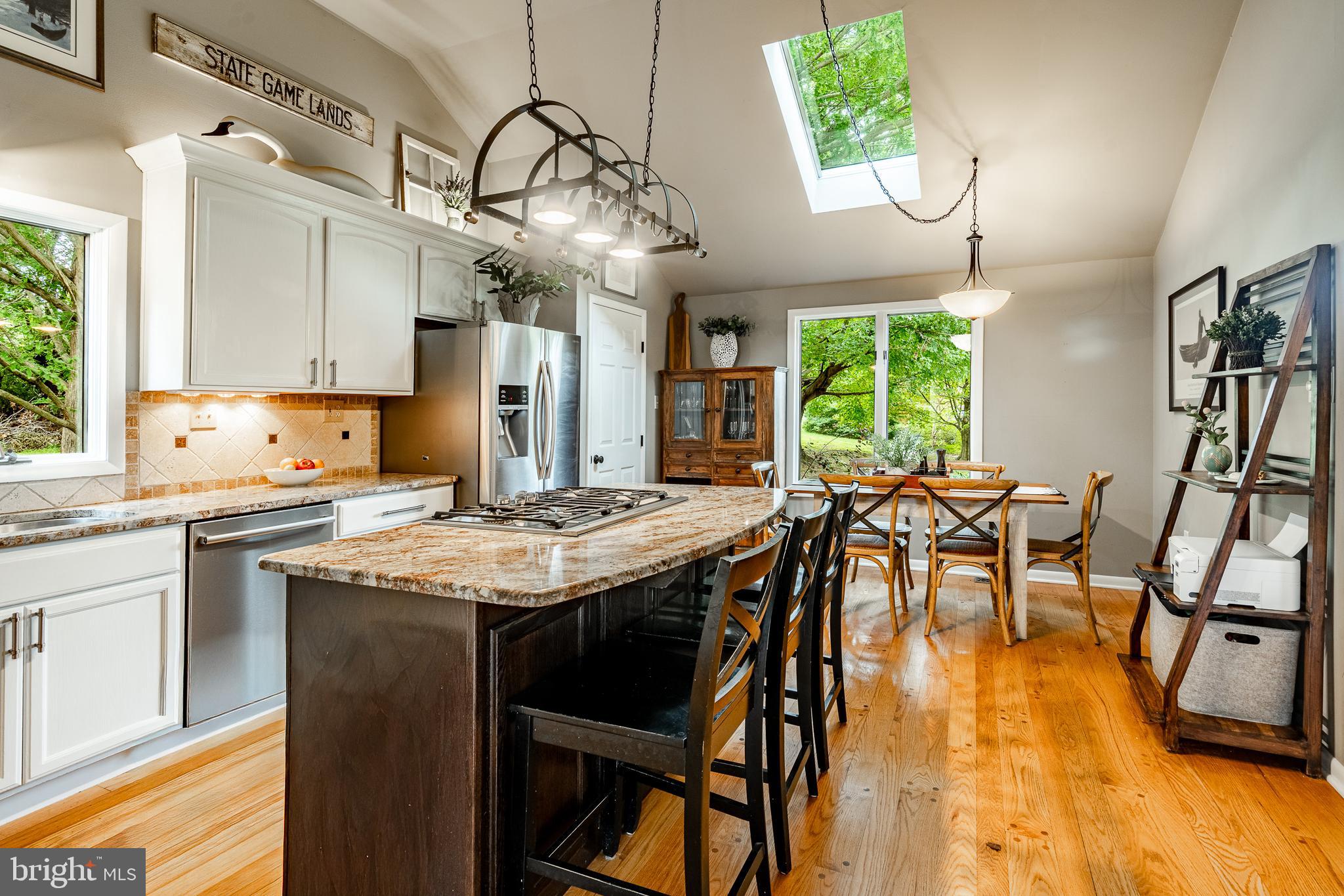 19 Ringfield Road, Unit 19 Chadds Ford, PA 19317 - Photo 13 of 39 a kitchen with stainless steel appliances granite countertop a stove a refrigerator a oven a dining table and chairs with wooden floor