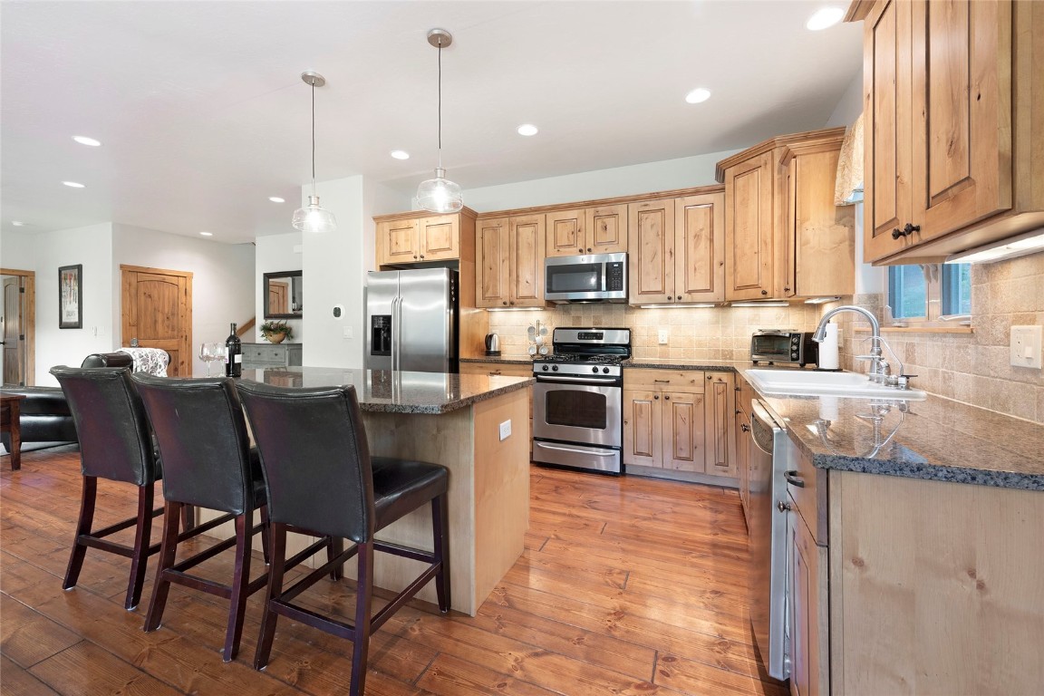 9 Davis Court Blue River, CO 80424 - Photo 12 of 44 a kitchen with stainless steel appliances granite countertop a stove top oven a sink a refrigerator white cabinets and a chairs with wooden floor
