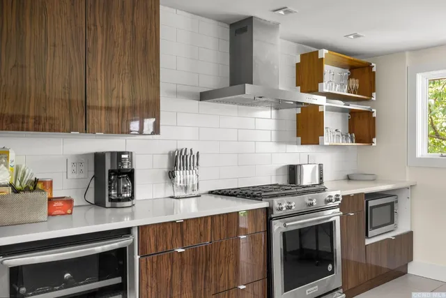 a kitchen with stainless steel appliances a stove a sink cabinets and a window