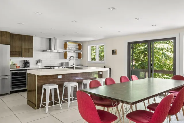 a kitchen with stainless steel appliances granite countertop a dining table chairs and a refrigerator