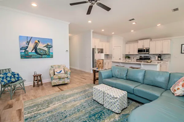 a living room with furniture kitchen view and a chandelier