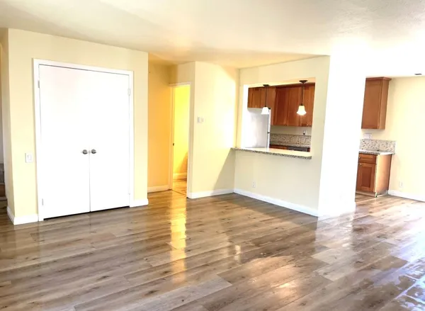 a view of a room with wooden floor and a refrigerator