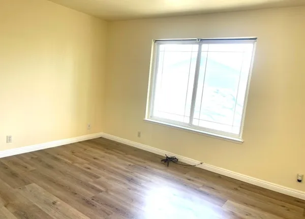 a view of a room that has wooden floor and a window