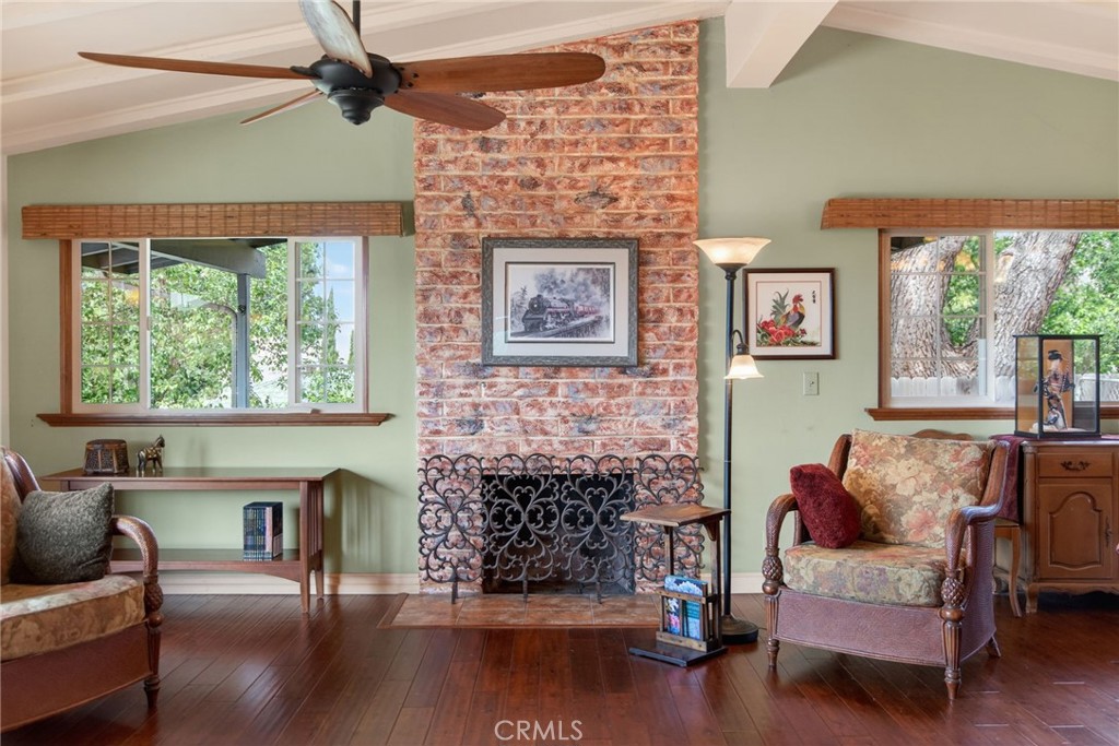 11543 Tulane Avenue Riverside, CA 92507 - Photo 13 of 49 The heart of the home features a floor-to-ceiling brick fireplace, creating a warm and inviting focal point in the living area. Large windows frame the fireplace, enhancing the serene, mid-century atmosphere.