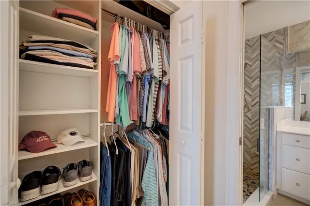 a view of walk in closet with clothes and shoes