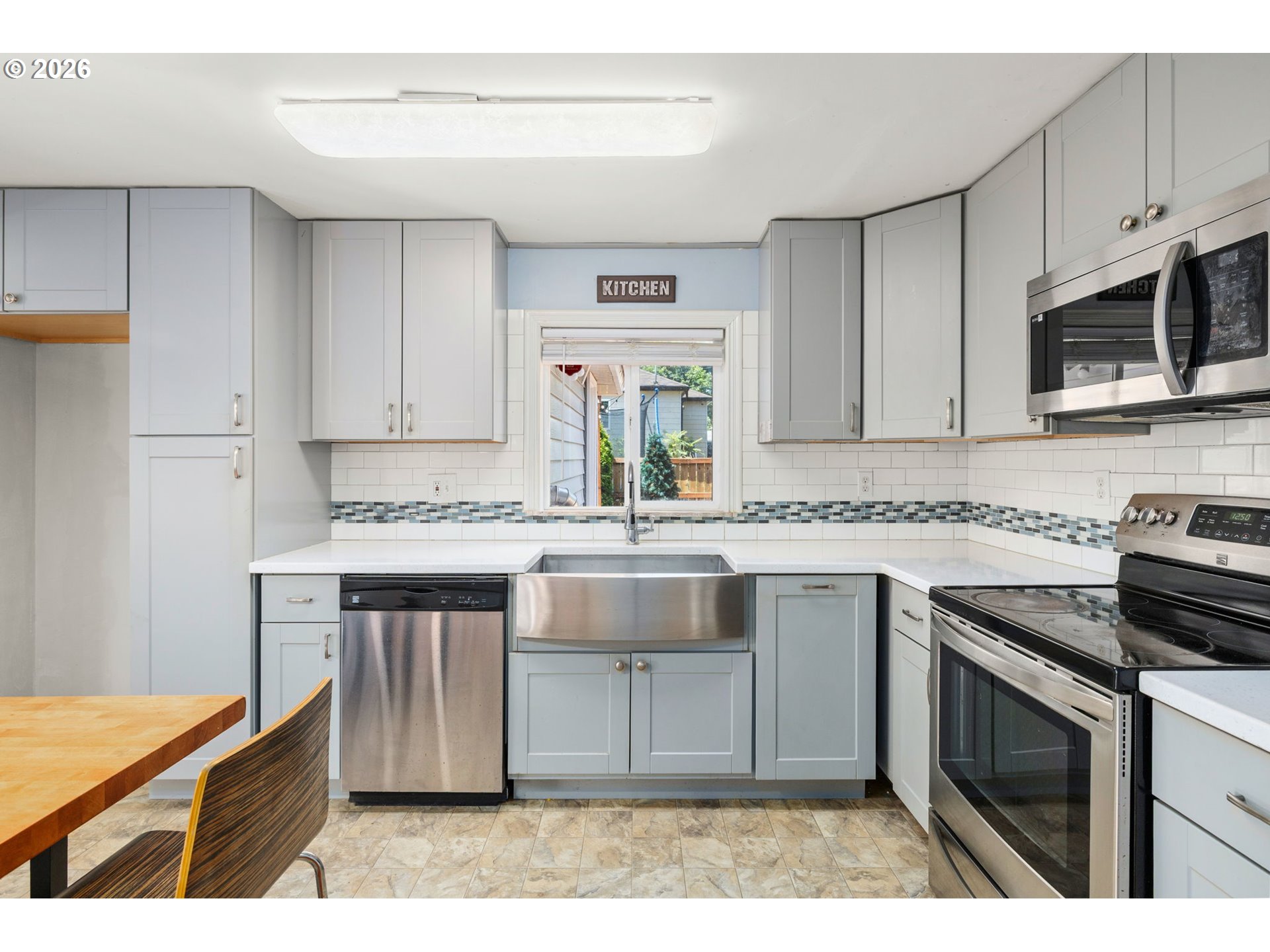 10245 Southeast Raymond Street Portland, OR 97266 - Photo 8 of 25 a kitchen with stainless steel appliances granite countertop a stove a sink dishwasher and a microwave oven with white cabinets
