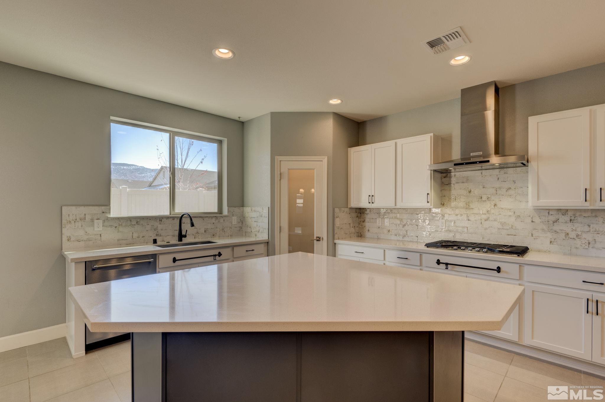 607 Riverbed Circle Reno, NV 89521 - Photo 6 of 40 a kitchen with kitchen island granite countertop a sink a stove a refrigerator cabinets and a counter top space