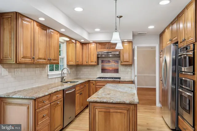 a kitchen with stainless steel appliances granite countertop a sink a stove and a refrigerator