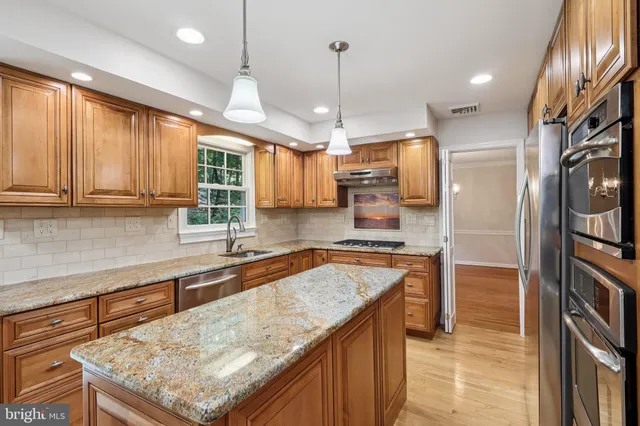 a kitchen with stainless steel appliances granite countertop wooden cabinets a sink a window and stainless steel appliances